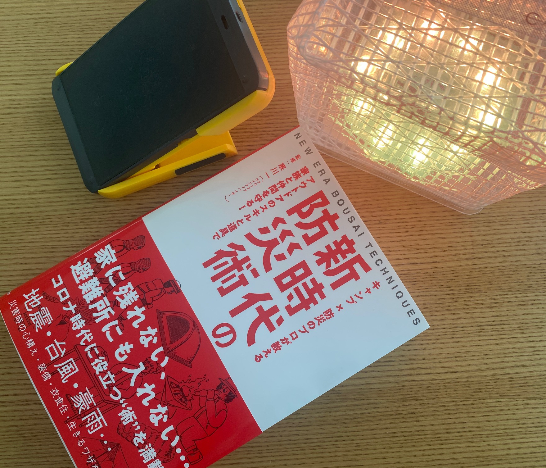 寒川一さん監修の最新刊「新時代の防災術」（発行:学研プラス）と、筆者個人所有のソーラーバッテリー、キャリーザサン（ソーラーライト）